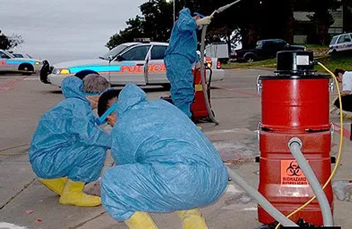 3 biohazard technicians cleaning biohazards off a street 