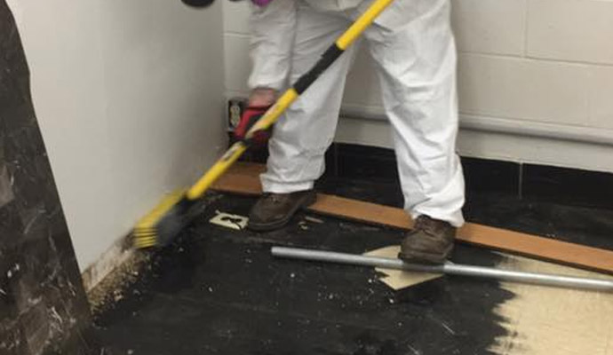 water restoration tech sweeping the floor